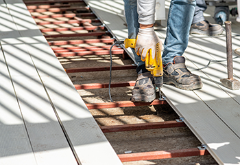 Worker using a drill to install composite decking by a pool in Panorama City backyard.